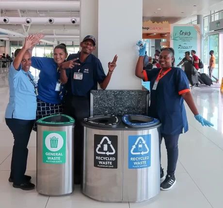 Four people at the airport of Curacao standing next to new recycling bins